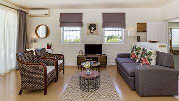A living room with a sofa, two armchairs, a coffee table, a TV, and a fireplace.