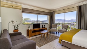 A hotel room with a large bed, a sofa, a TV, and a view of mountains. -  Morgen Guest House (Cape Town)