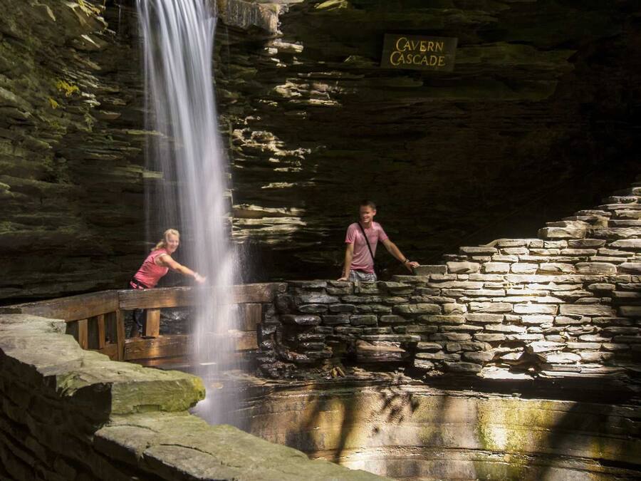 A cave with a waterfall, a stone bench, and a sign reading "Cavern Cascade".