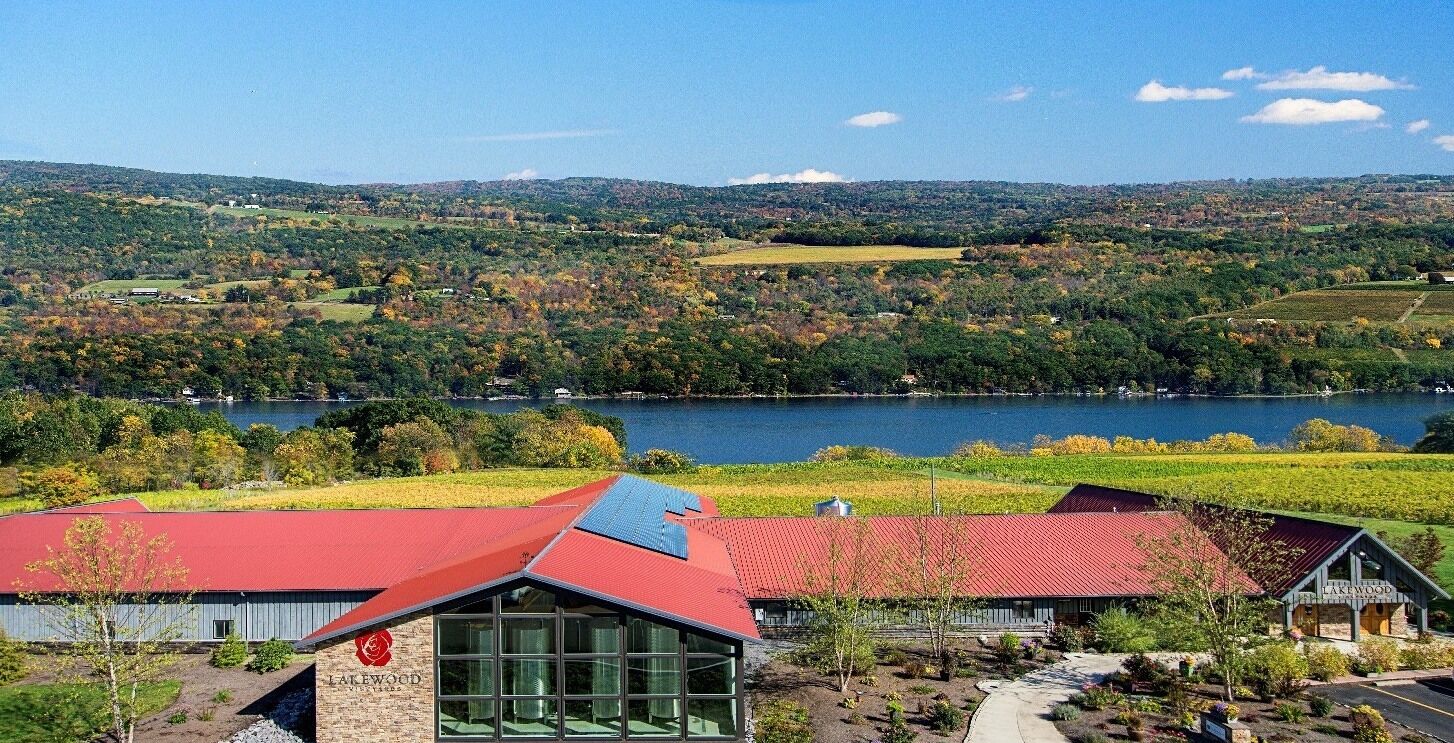 A lakeside property with a red-roofed building, a stone building with a glass facade, and a sign reading "Lakewood."