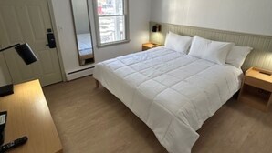 A bedroom with a large bed, bedside tables, a mirror, a door, and a window.