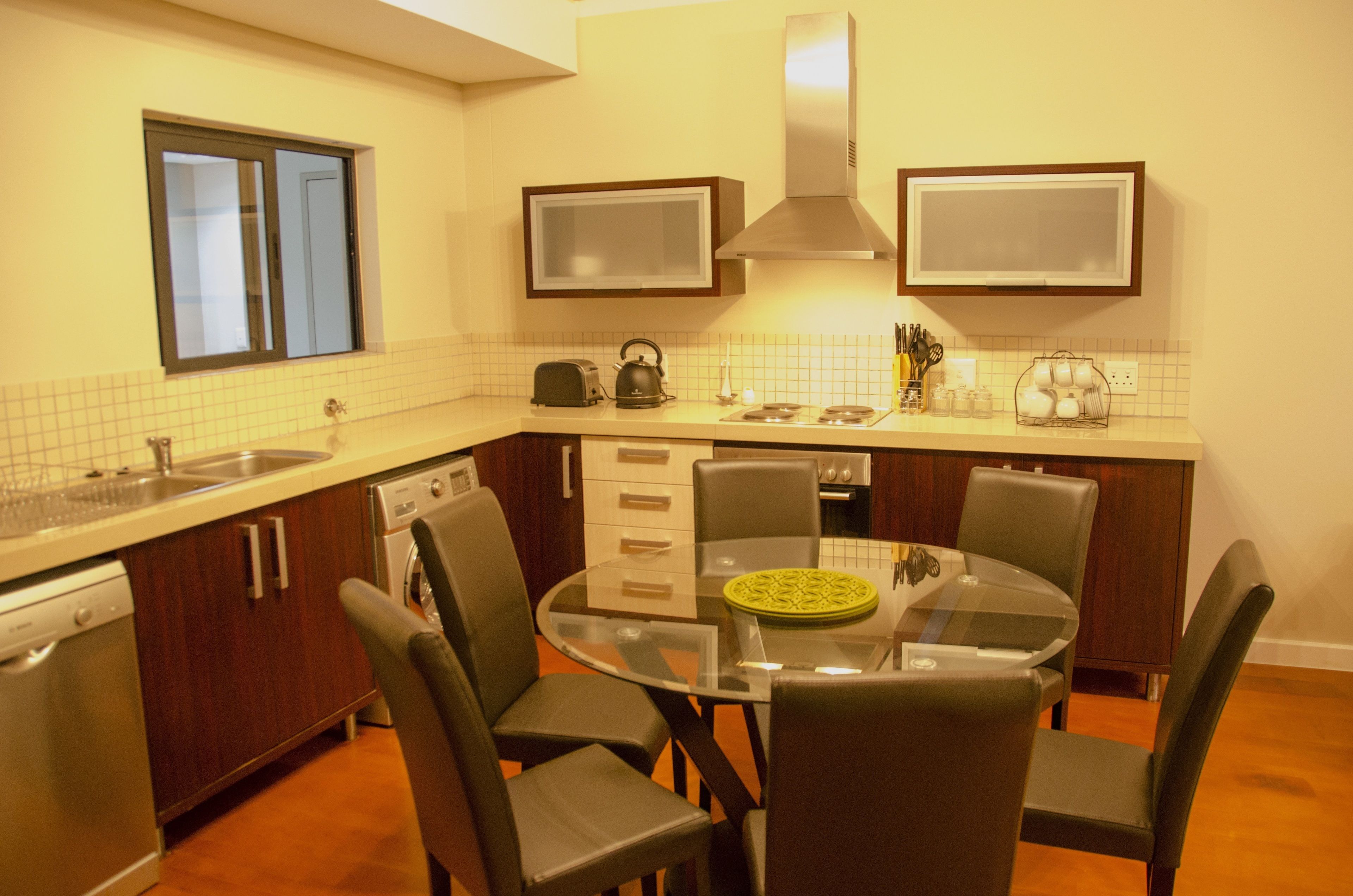 A compact kitchen with a dishwasher, a microwave, and a stove. There is a dining table with four chairs.