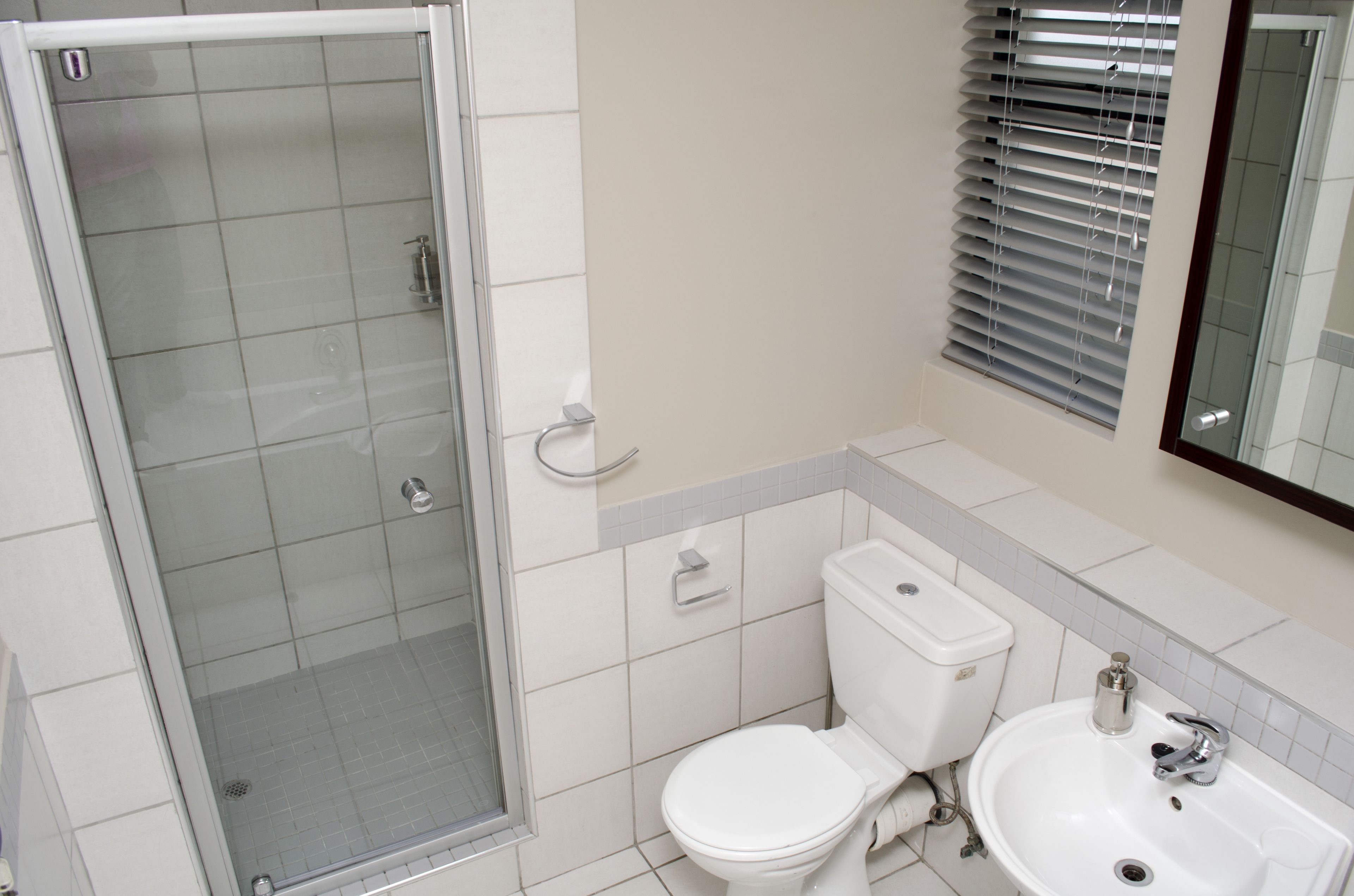 Un baño moderno con ducha vidriada, inodoro y lavamanos.