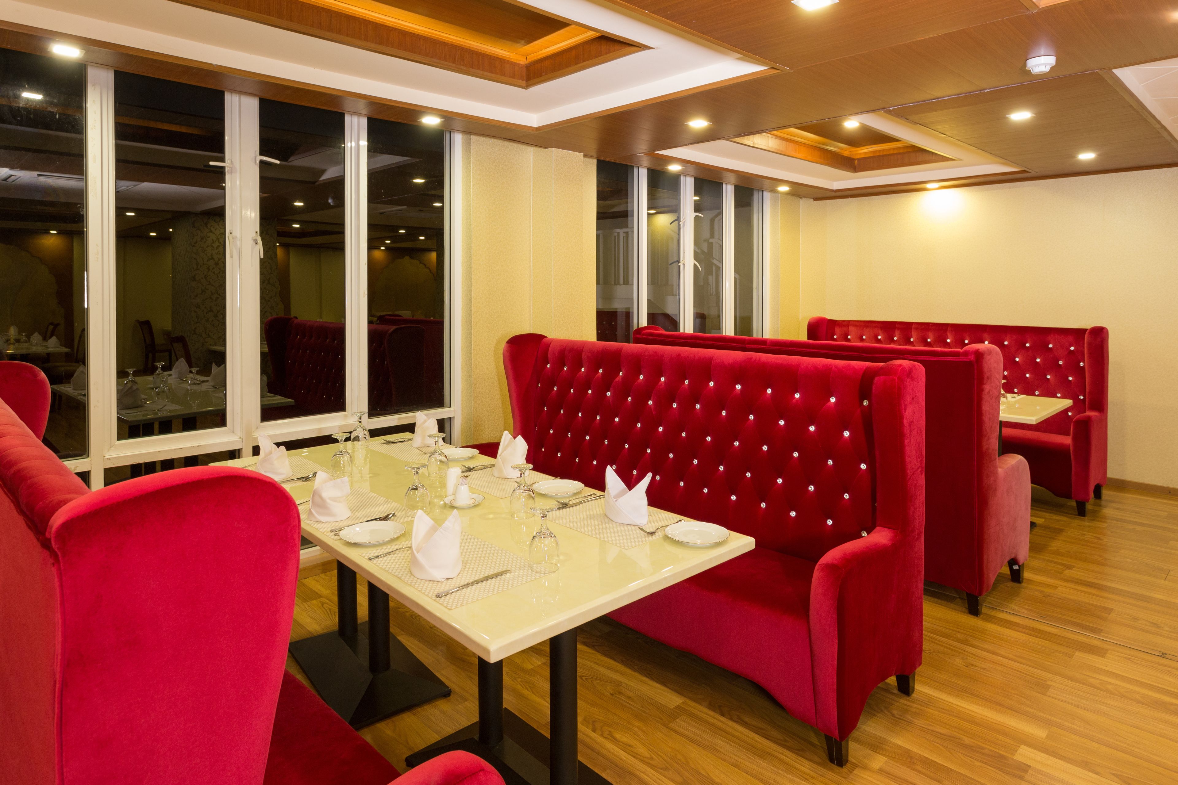 Un restaurante con cabinas tapizadas en rojo, suelo de madera y amplios ventanales.