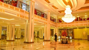 Un hall d’entrée spacieux, agrémenté d’un magnifique lustre, de balustrades décorées et d’un comptoir de réception.