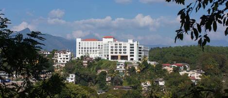 A multi-story building with a red roof, surrounded by greenery and other buildings.