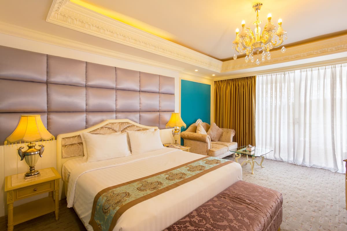 Ein Hotelzimmer mit einem großen Bett, einer Couch, einem Glastisch und einer Deckenleuchte.
