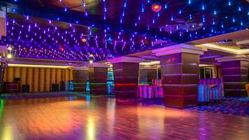 Un hall espacioso con suelo de madera, varias zonas de estar y un techo decorado con lámparas colgantes.