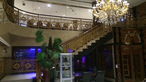 A grand staircase with ornate railings, a chandelier, and a display of figurines. - Sun Beach Hotel (Cotonou)