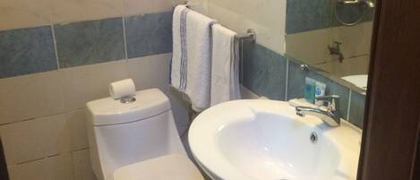 Un baño con inodoro, bidé y lavamanos.