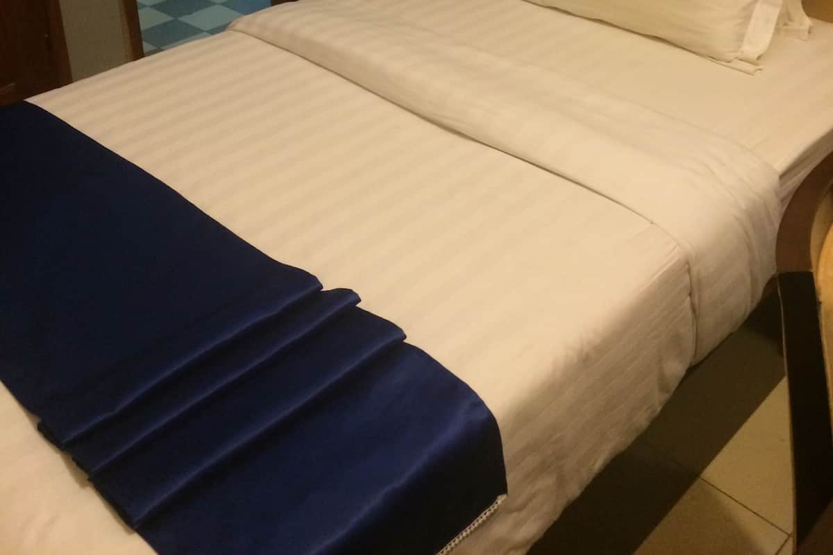A hotel room with a bed, a bedside table, and a bathroom visible through an open door.