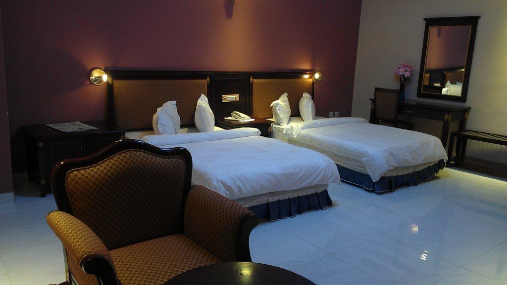 Habitación de hotel con dos camas, una silla, una mesa, un escritorio y un espejo.
