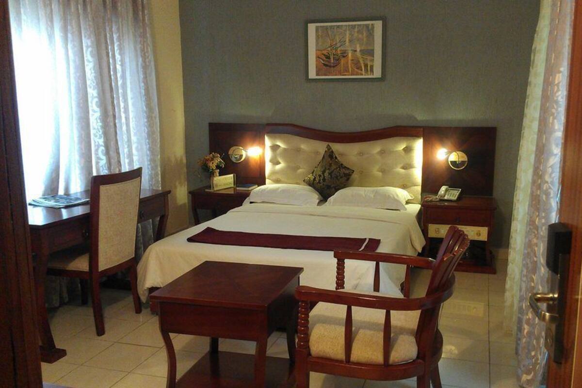 A hotel room with a bed, bedside tables, a desk, and a chair.