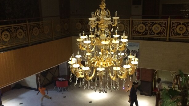A grand lobby with a large chandelier, a red velvet sofa, and a glass railing. - Sun Beach Hotel (Cotonou)