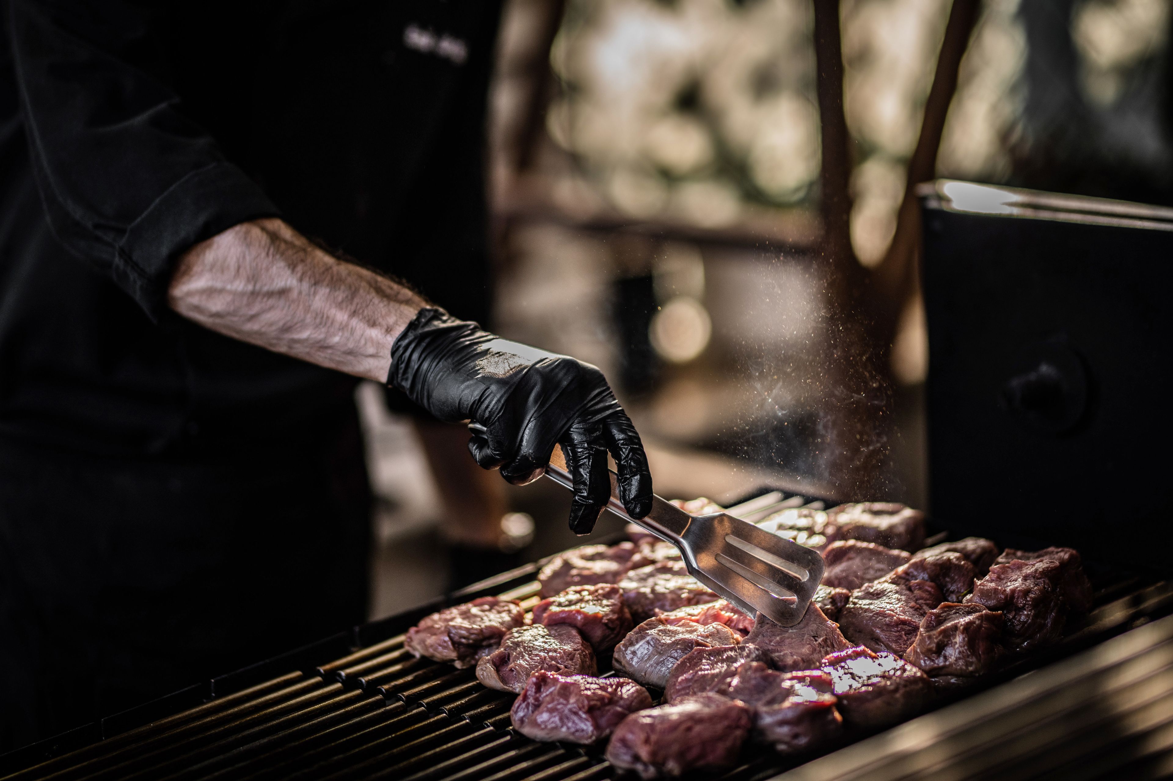 A person grilling meat on an outdoor grill.