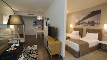 Una habitación de hotel con cama, escritorio, silla, televisor y kitchenette.