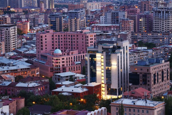 A dense urban area with various buildings, including a prominent pink building with a dome and a tall modern building with illuminated windows.