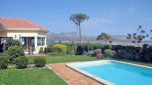 Ein Haus mit Swimmingpool, Terrasse und Blick auf Berge und Meer.