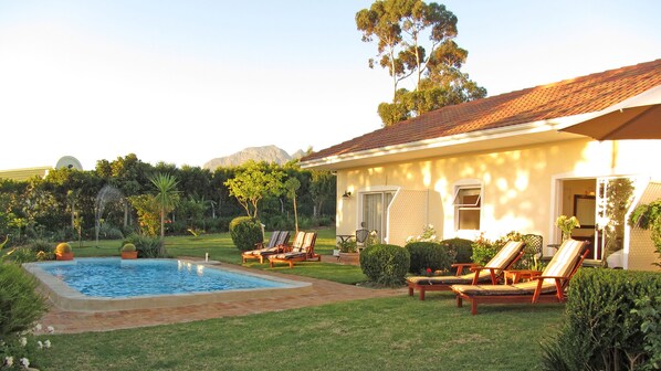 A house with a swimming pool, outdoor seating, and a garden. - Somerset Sights Bed and Breakfast (Cape Town)