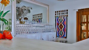 A bar area with a mirrored wall, a peacock feather decoration, and a colorful woven wall hanging. - Belinda Hotel (Kas)