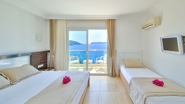 A hotel room with two beds, a TV, and a balcony with a view of the sea. - Belinda Hotel (Kas)