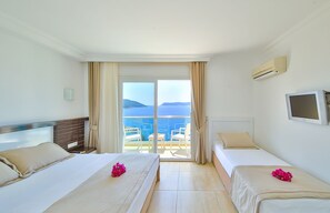 Habitación de hotel con dos camas, televisor y balcón con vista al mar.