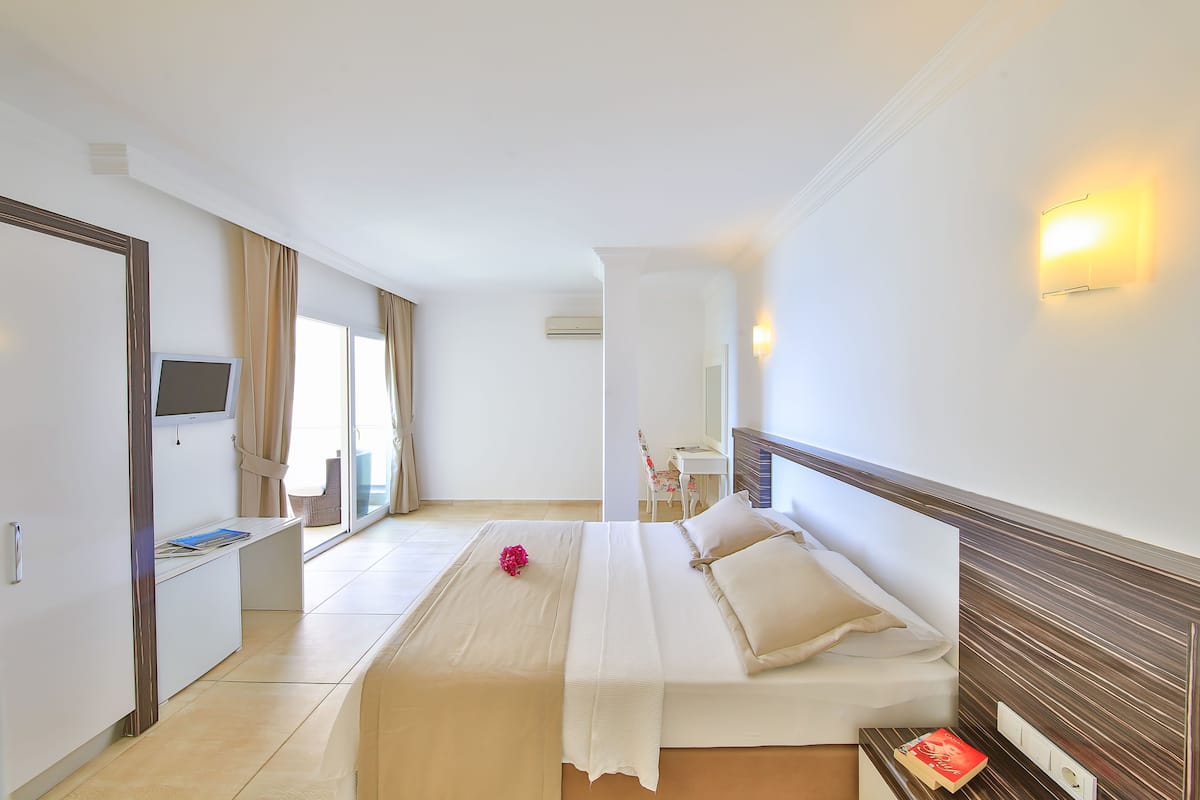 A hotel room with a bed, a desk, a TV, and a window with curtains.