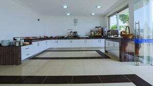 A modern kitchen with a central island, white cabinetry, and a glass door leading to a balcony. - Belinda Hotel (Kas)