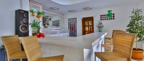 A modern kitchen with a white countertop, wicker chairs, and a large speaker.