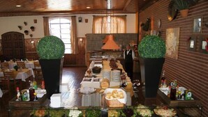 A buffet setup with various food items and a waiter. - Hotel Fazenda São Matheus (Serra Negra)