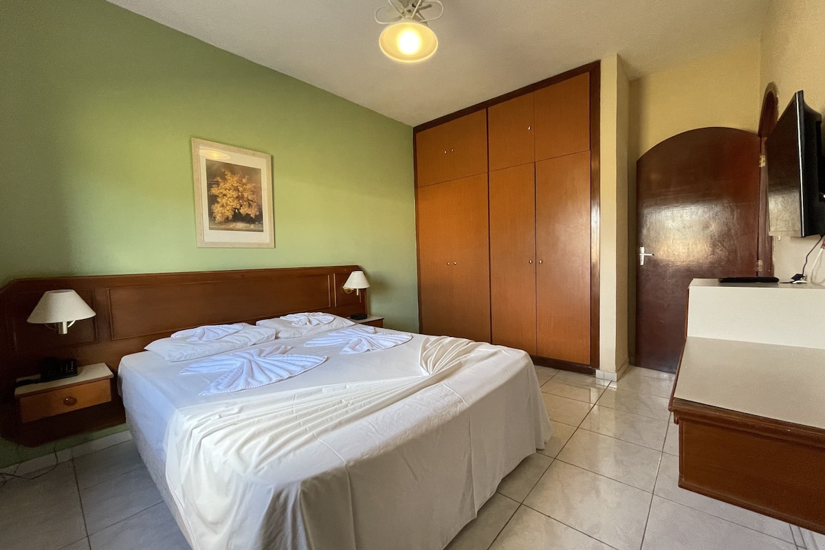 Een hotelkamer met een bed, nachtkastjes, een kledingkast en een televisie.