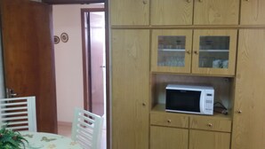 A kitchen with wooden cabinets, a microwave, and a dining area with a table and chairs.