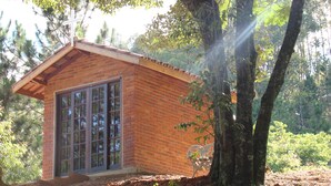 A small brick building with large windows, surrounded by trees and natural vegetation.