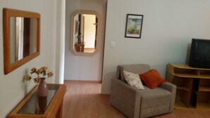 A living room with a sofa, a TV stand, a mirror, and a framed picture on the wall.