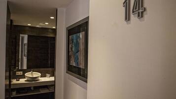 Ein Flur mit der Nummer 14 an der Wand, einem gerahmten Bild und einem modernen Badezimmer mit Waschbecken und Spiegel.
