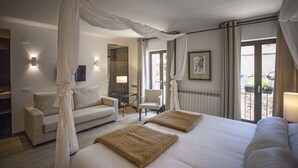 A hotel room with a large bed, two armchairs, a small table, and a balcony with curtains. - Hotel Pura Vida (Valganon)