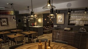 A restaurant interior with wooden tables, hanging pendant lights, and a bar area with glasses and bottles. - Hotel Pura Vida (Valganon)