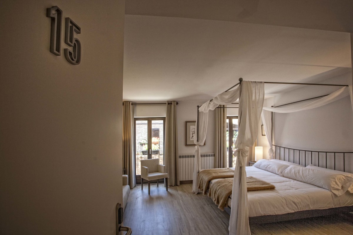A bedroom with a four-poster bed, a chair, and a number '15' on the wall.