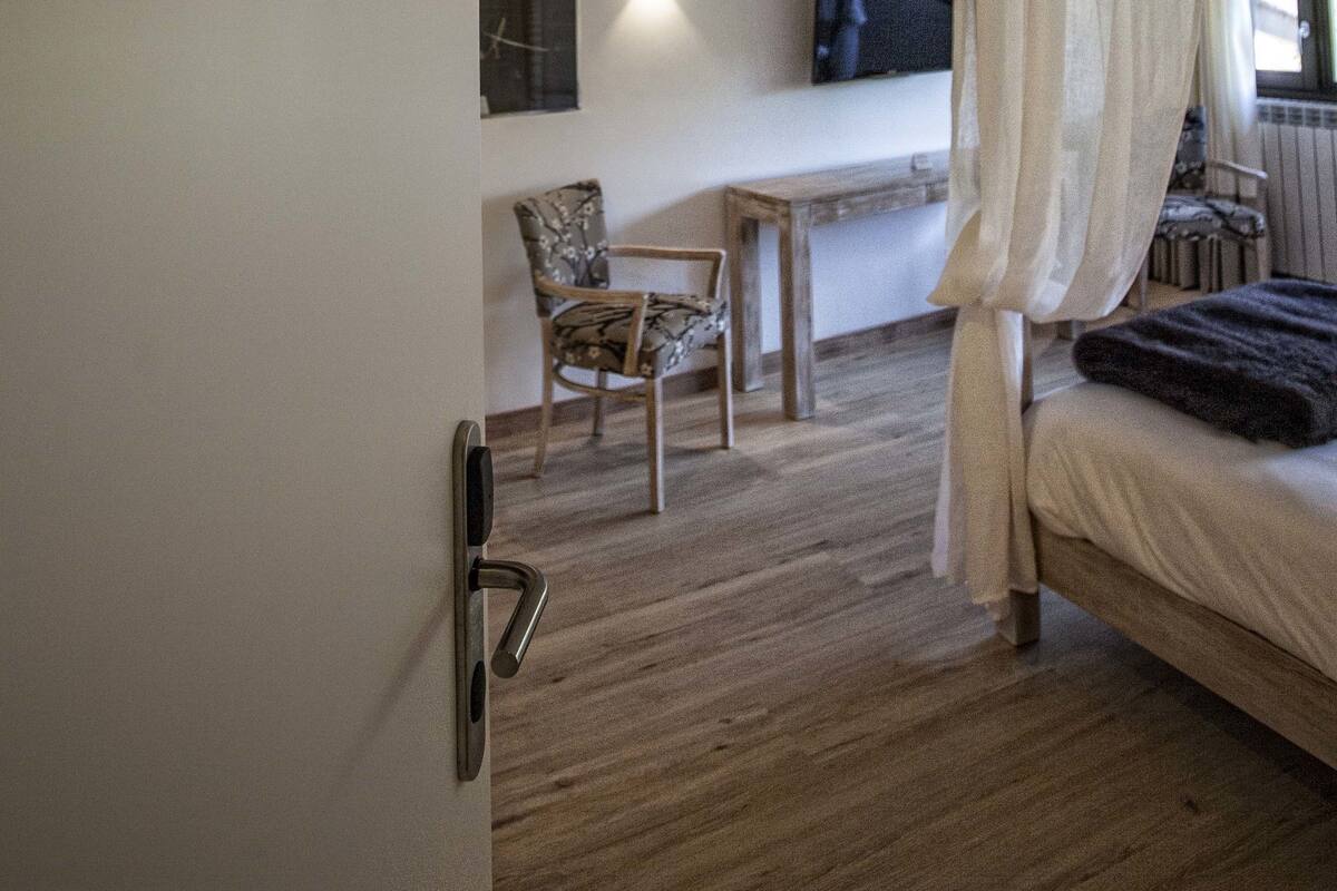 A bedroom with a canopy bed, a television mounted on the wall, and a wooden floor.