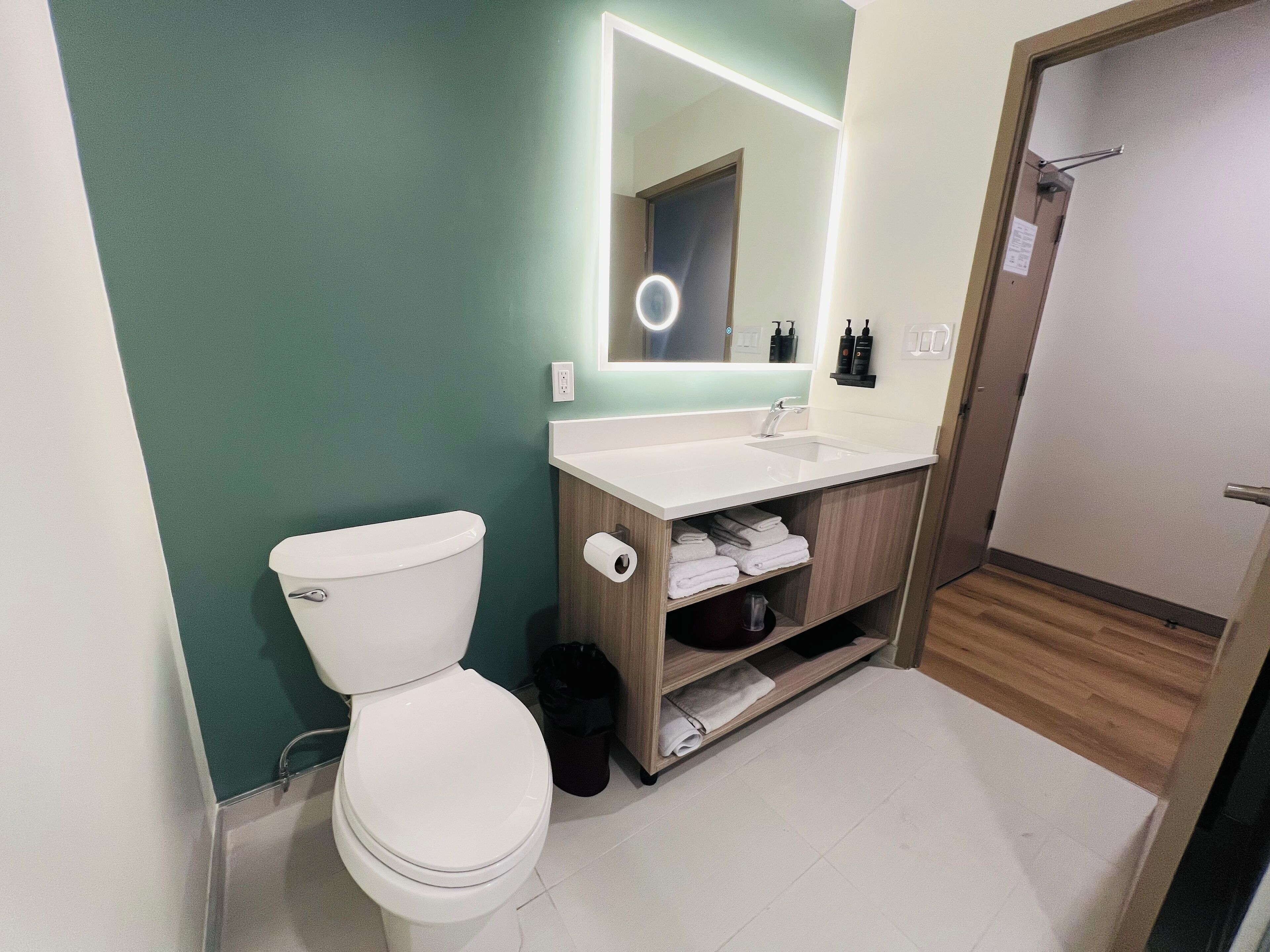A modern bathroom with a white toilet, a sink with a mirror, and a shower area.