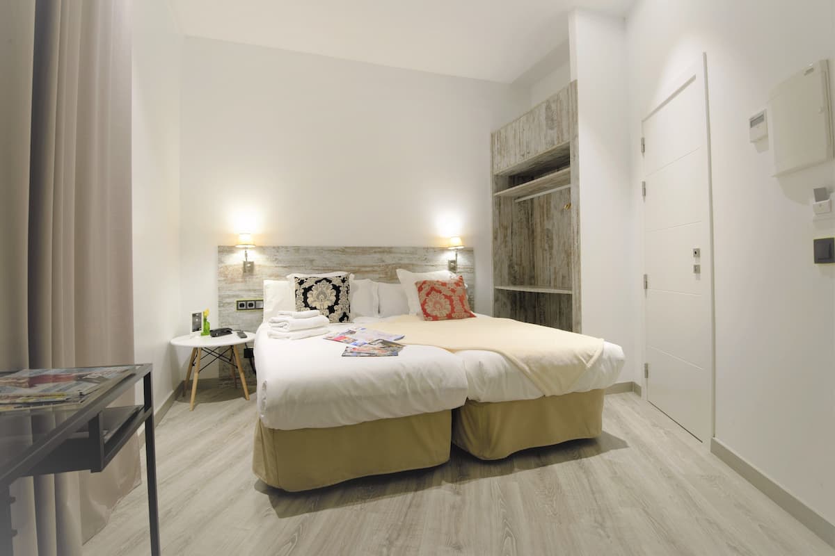 A hotel room with a double bed, bedside tables, a small desk, and a wardrobe.