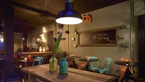 A cozy restaurant interior with wooden tables, teal chairs, and a chalkboard menu. -  Staytion Urban City Hotel Mannheim (Mannheim)