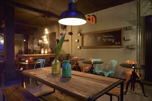 A cozy restaurant interior with wooden tables, teal chairs, and a chalkboard menu.