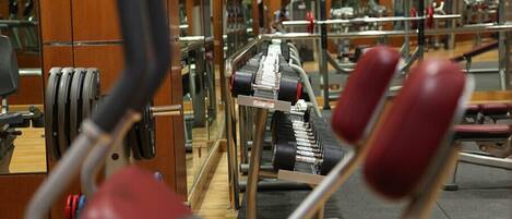 Une salle de sport équipée de matériel de musculation, notamment des barres et un banc.