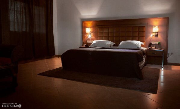 Una habitación de hotel con cama, mesitas de noche y un escritorio.