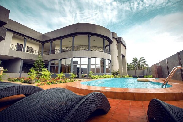 Een buitenzwembad, parasols bij het zwembad en ligstoelen