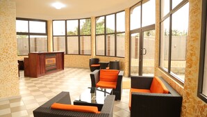 A lobby with a reception desk, check-in counter, and seating area with chairs and tables. - Mint Hotel (Lomé)