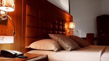 A hotel room with a tufted headboard, a bedside telephone, and patterned pillows.
