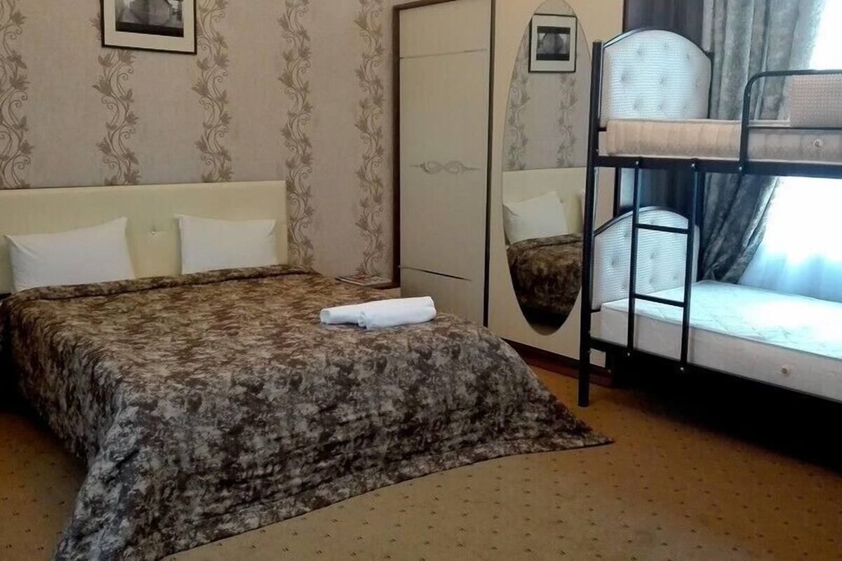 Ein Schlafzimmer mit einem großen Bett, einem Etagenbett, einem Kleiderschrank und einem Spiegel.
