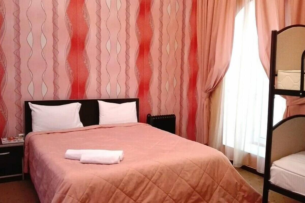 Ein Schlafzimmer mit einem Einzelbett, einem Etagenbett, einem Nachttisch und einer Wand mit einem gewellten Muster.